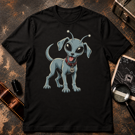 A black short-sleeve crewneck t-shirt featuring a cartoon graphic of a light blue puppy with large eyes, a red collar, and a gold tag, displayed against a textured gray background.