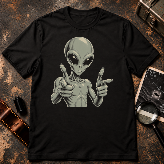 A black short-sleeve crewneck t-shirt featuring a graphic print of a classic alien pointing forward, set against a textured gray background.