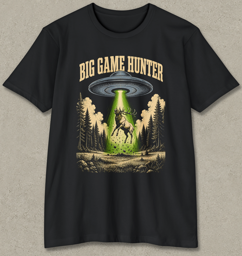 A black short-sleeve graphic t-shirt featuring a 'Big Game Hunter' theme. The graphic shows a green beam from a UFO shining down onto a deer in a forest, with the text 'BIG GAME HUNTER' printed above in a tan serif font.