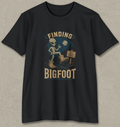 A black short-sleeve crewneck t-shirt with a vintage-style graphic on the front showing a Bigfoot alien in boots next to a sign that reads 'KEEP BIGFOOT LEGENDS ALIVE'.