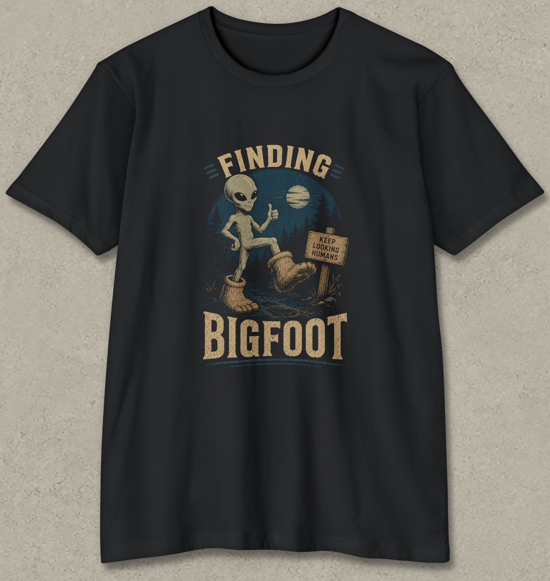 A black short-sleeve crewneck t-shirt with a vintage-style graphic on the front showing a Bigfoot alien in boots next to a sign that reads 'KEEP BIGFOOT LEGENDS ALIVE'.