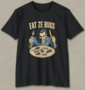 A black short-sleeve graphic t-shirt featuring a retro-style illustration of a man holding a fork and knife over a plate of bugs, with the text 'EAT ZE BUGS' printed above. The t-shirt is displayed flat against a textured gray background.