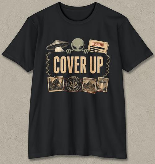 A black short-sleeve crewneck t-shirt with a vintage-style graphic on the front featuring a green alien, a UFO, a 'TOP SECRET' document, and the words 'COVER UP' in beige, displayed against a textured gray background.