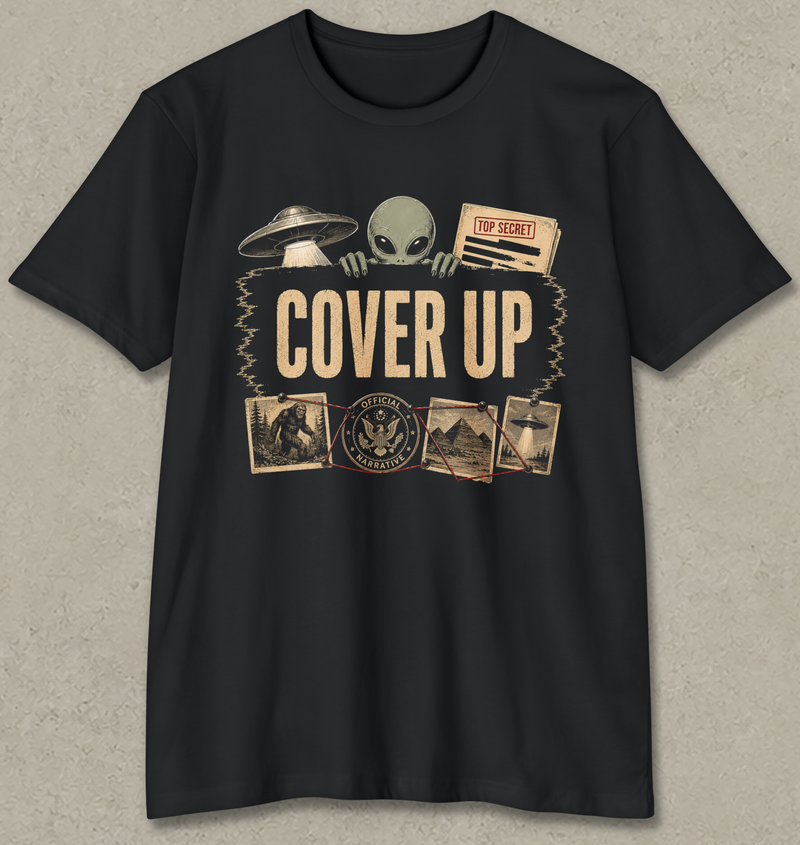 A black short-sleeve crewneck t-shirt with a vintage-style graphic on the front featuring a green alien, a UFO, a 'TOP SECRET' document, and the words 'COVER UP' in beige, displayed against a textured gray background.