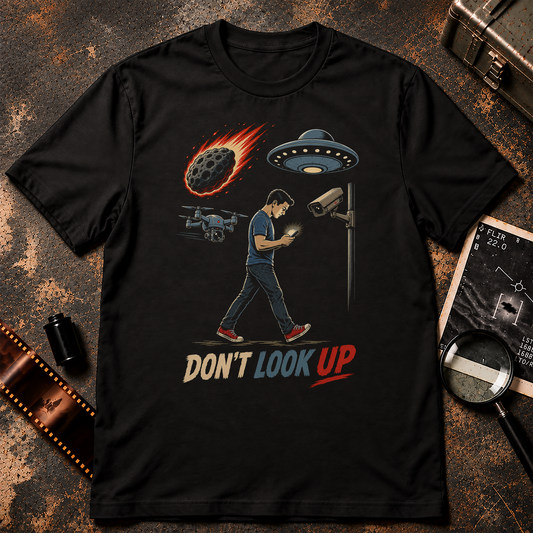 DON’T LOOK UP shirt design featuring a man staring at his phone while a UFO, surveillance drone, security camera, and incoming meteor surround him.