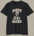 A black short-sleeve graphic t-shirt featuring a retro-style alien holding a coffee cup with 'EARTH' written above and 'SUCKS' below, displayed on a textured gray background.