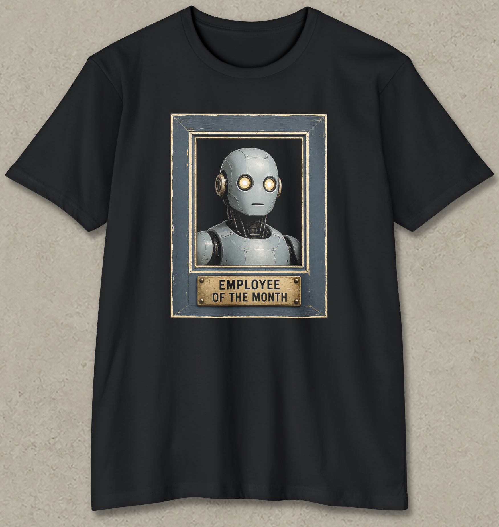 A black short-sleeve crewneck t-shirt featuring a graphic print of a silver robot head inside a blue-gray frame with a gold plaque below that reads 'EMPLOYEE OF THE MONTH'.