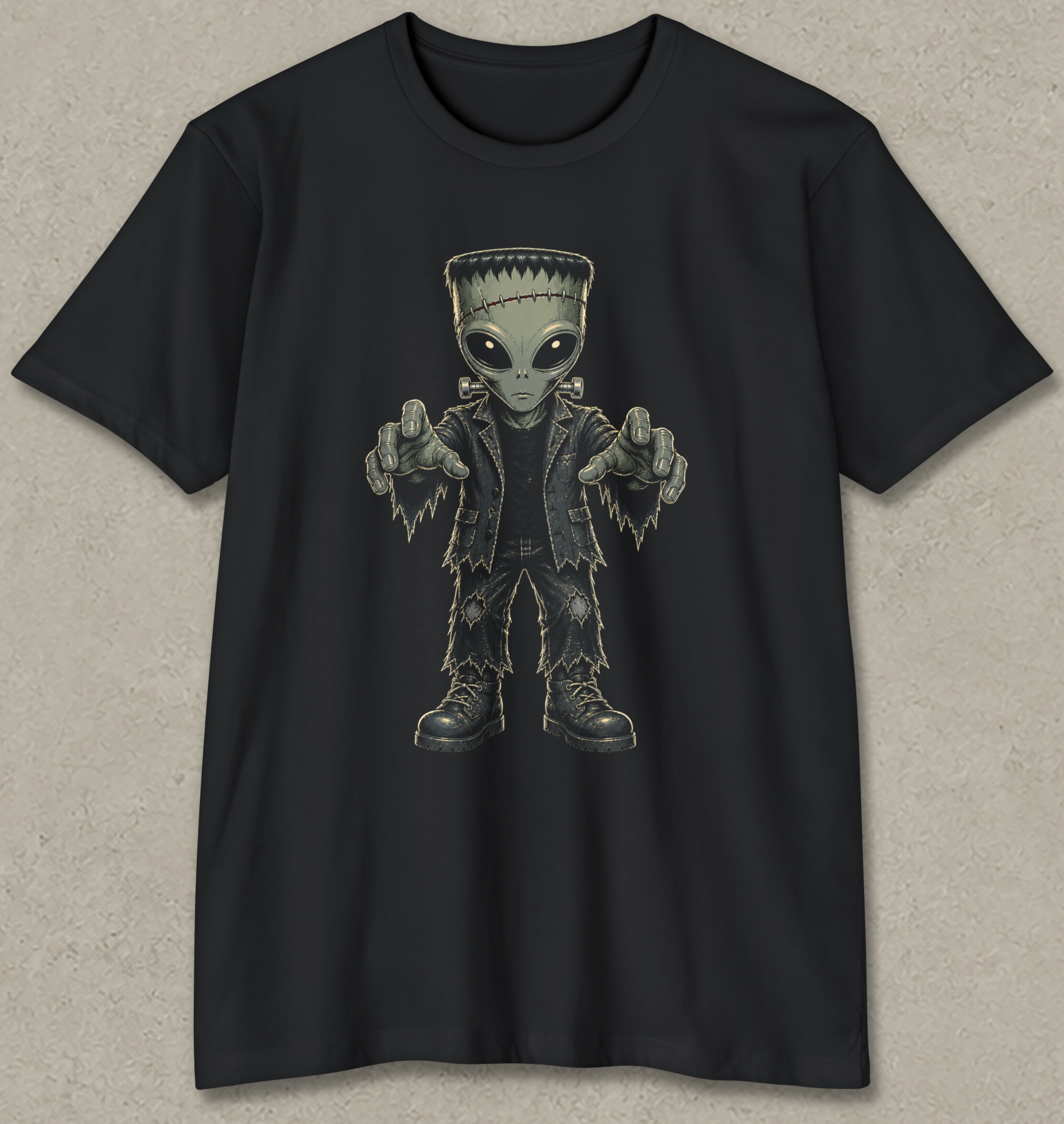A black short-sleeve crewneck t-shirt featuring a graphic of a Frankenstein's monster-like alien with large eyes, pointing forward, displayed against a textured gray background.
