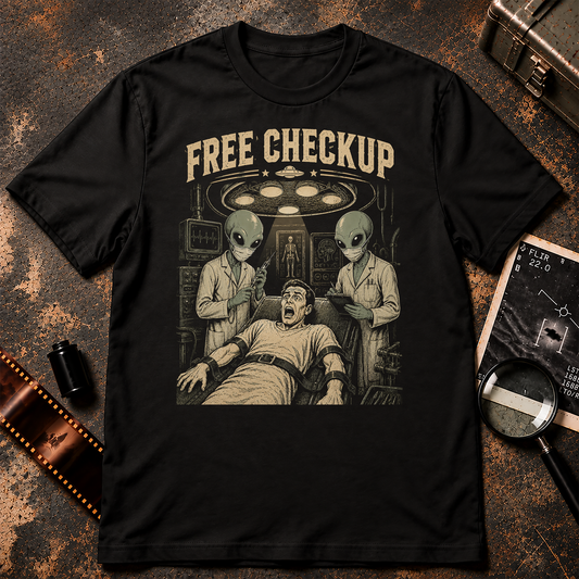 A black short-sleeve crewneck t-shirt with a vintage-style graphic print on the front. The graphic features the text 'FREE CHECKUP' in a distressed beige font above an illustration of a man in a hospital gown surrounded by two green-skinned aliens under a surgical light.