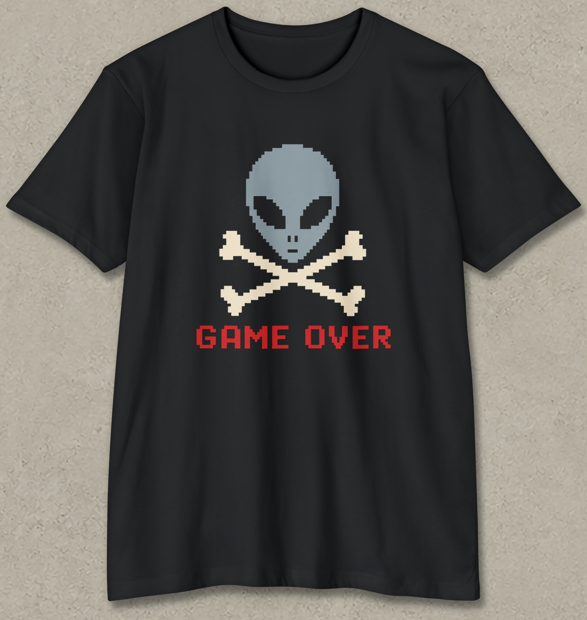 A black short-sleeve t-shirt with a pixel-art graphic of a gray alien skull and crossbones above the red text 'GAME OVER' on a textured gray background.