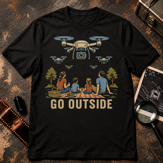 GO OUTSIDE shirt design featuring a family having a picnic while multiple surveillance drones with cameras hover overhead.