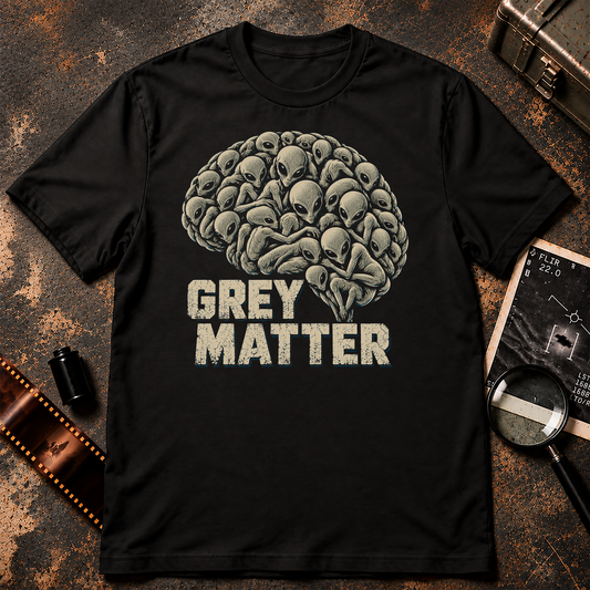 Grey Matter T-Shirt design featuring dozens of small Grey aliens with oversized heads and large black eyes clustered together to form the shape of a human brain. Bold distressed cream lettering reads GREY MATTER beneath the illustration, with subtle blue accents against a black background.