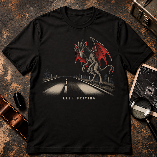Keep Driving Jersey Devil shirt graphic featuring a horned winged cryptid standing beside a dark highway at night