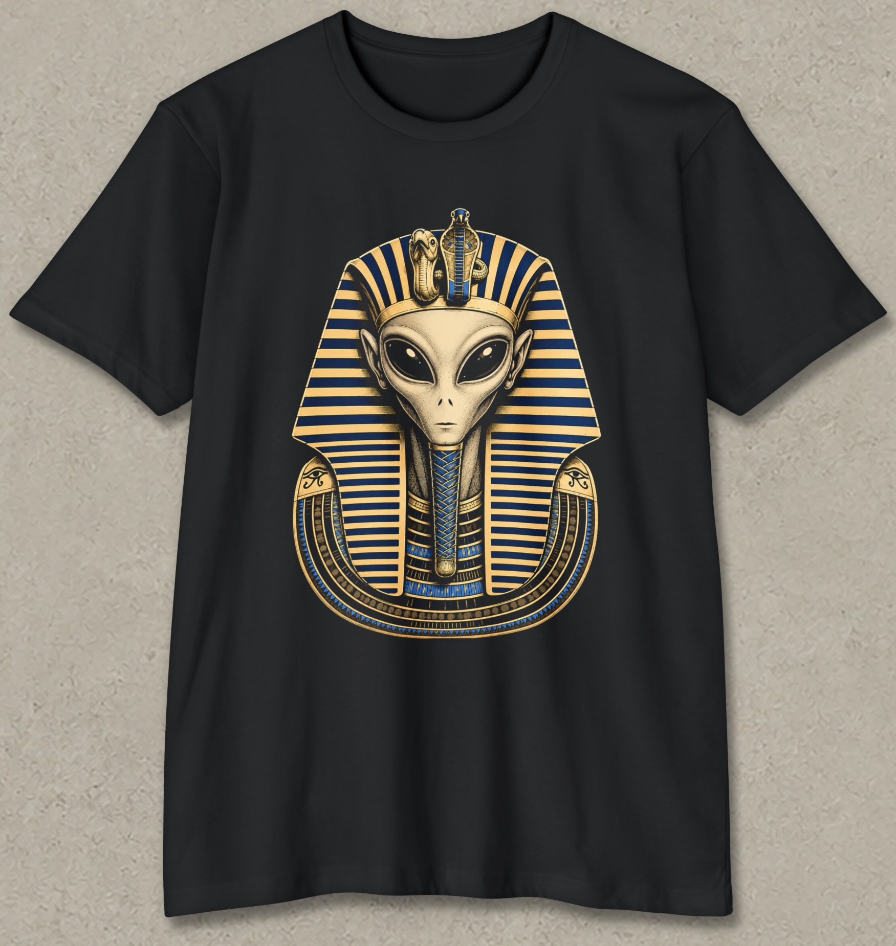 A black short-sleeve crewneck t-shirt featuring a graphic of an alien styled like Pharaoh with a gold and blue striped headdress, displayed against a textured gray background.
