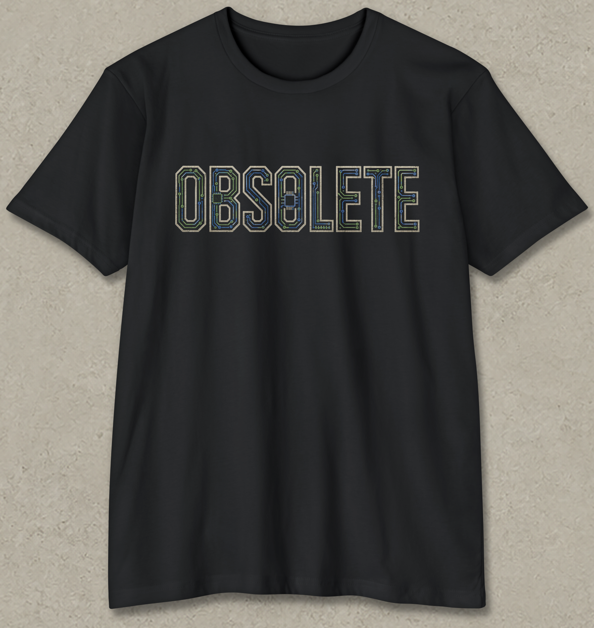 A black short-sleeve crewneck t-shirt with the word 'OBSOLETE' printed across the chest in a retro, outlined font. The letters are filled with a camouflage pattern in shades of green, blue, and brown.