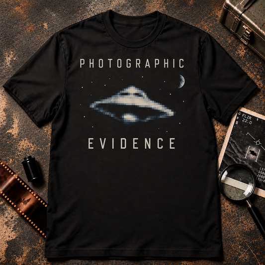PHOTOGRAPHIC EVIDENCE shirt design featuring a pixelated flying saucer, crescent moon, stars, and cream archival-style lettering on a black background.