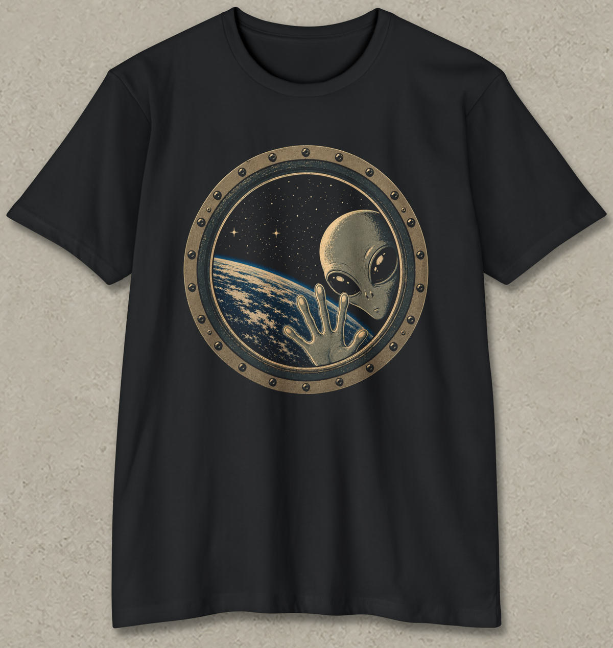 A black short-sleeve crewneck t-shirt featuring a circular graphic print of a classic silver-grey alien waving from space, with Earth visible in the background.