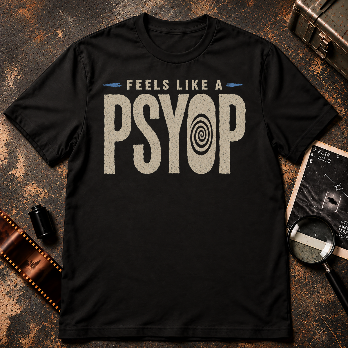 Minimalist conspiracy graphic with distressed cream lettering reading “FEELS LIKE A PSYOP” against a black background. The letter O in PSYOP contains a black hypnotic spiral, with small blue accent marks on either side of the upper text.