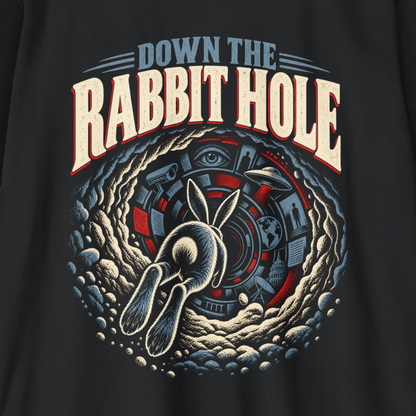A close-up of a black t-shirt featuring a large graphic print with the text 'DOWN THE RABBIT HOLE' in cream and red, surrounding a detailed illustration of a rabbit diving down into a portal.