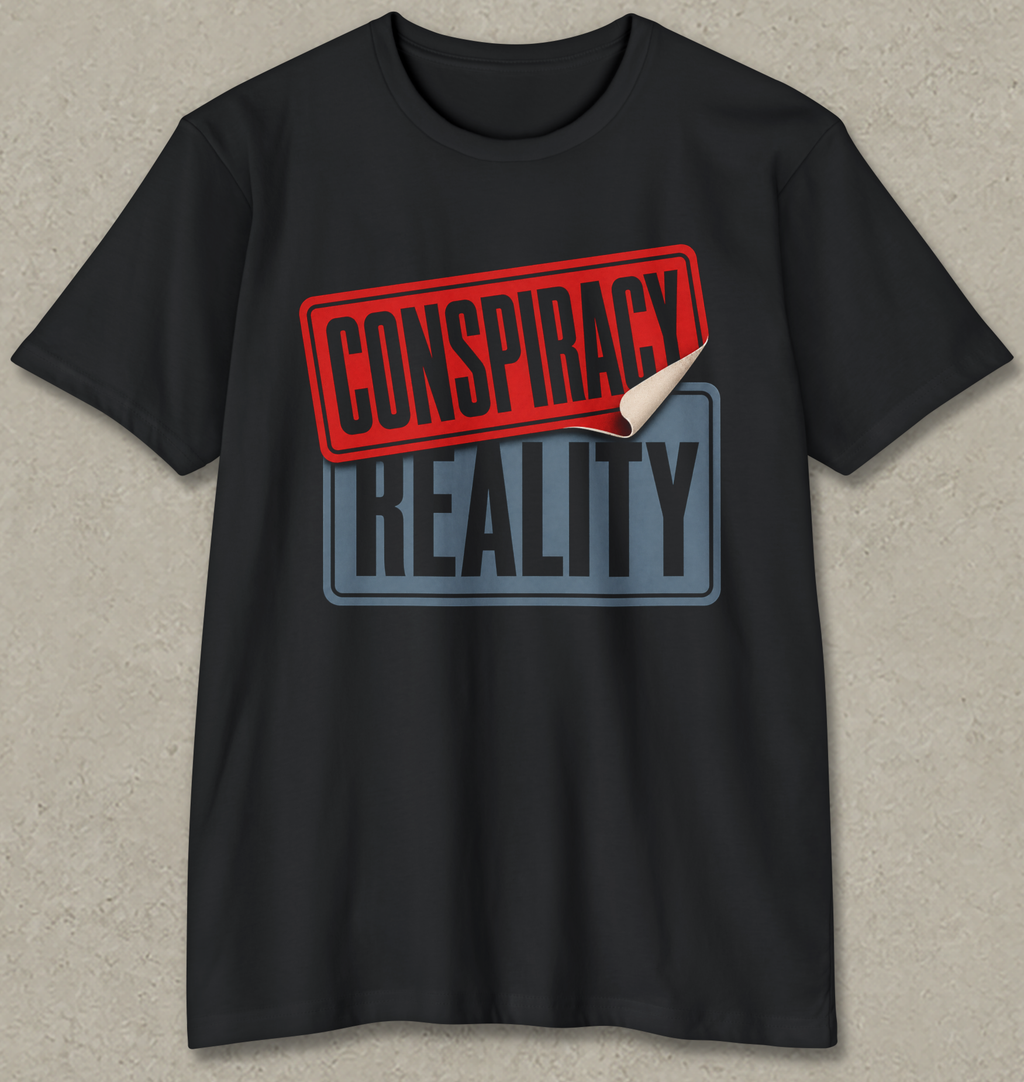 A black short-sleeve t-shirt with a graphic print reading 'CONSPIRACY REALITY' on the chest. The top stamp is red with a curled-down bottom corner revealing a white underside, and the bottom stamp is blue-gray.