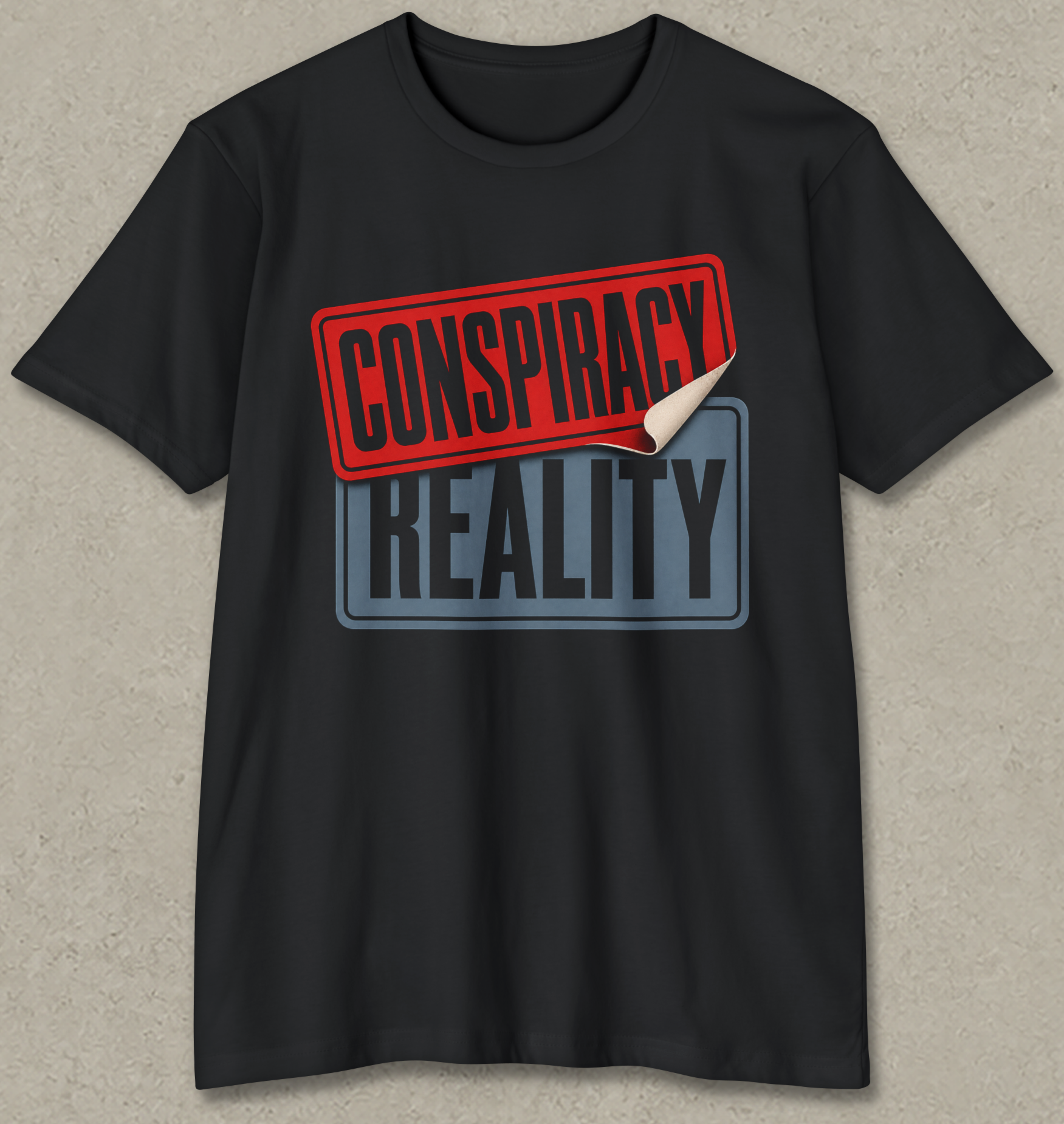 A black short-sleeve t-shirt with a graphic print reading 'CONSPIRACY REALITY' on the chest. The top stamp is red with a curled-down bottom corner revealing a white underside, and the bottom stamp is blue-gray.