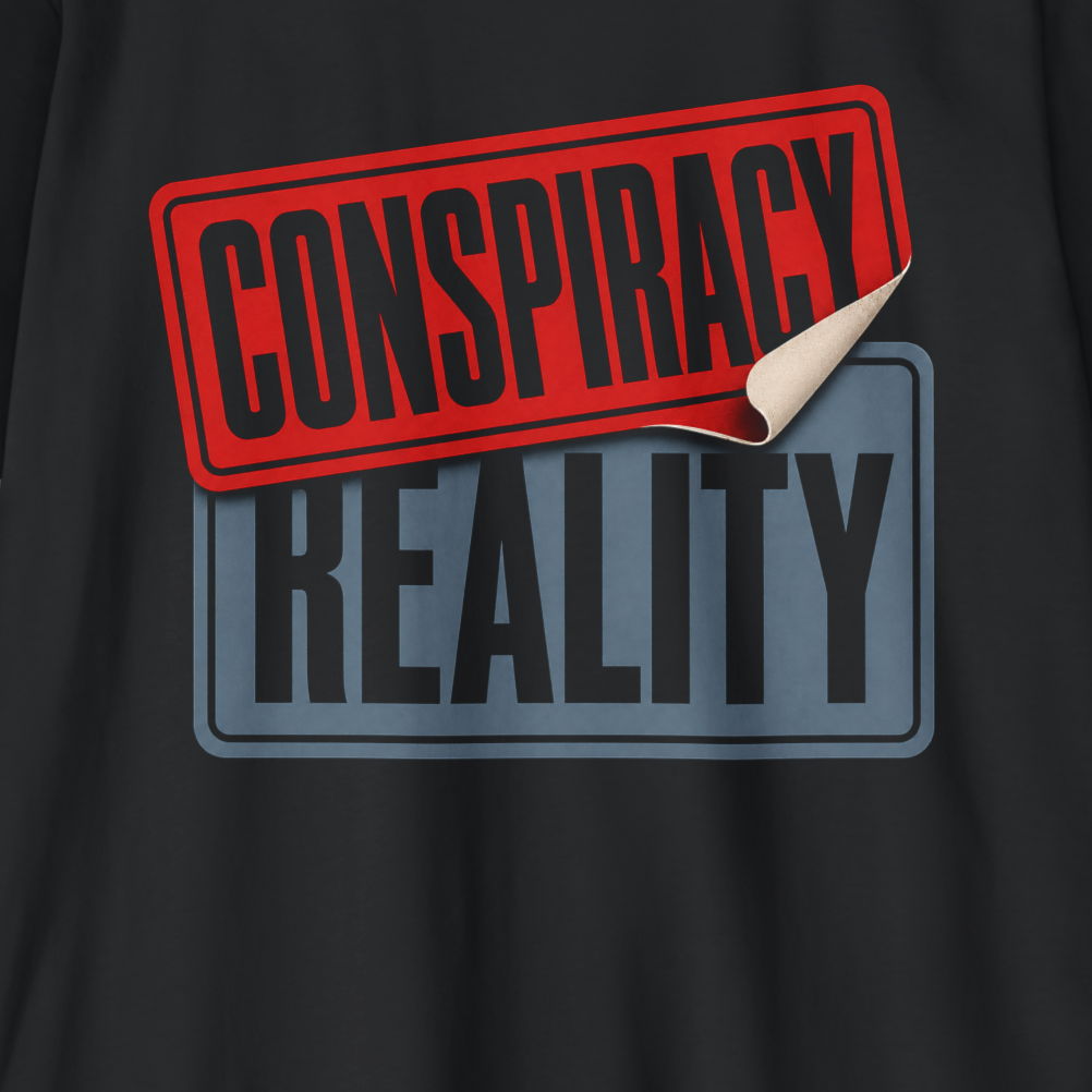 A close-up of a black graphic print featuring a red stamp that says 'CONSPIRACY' with a curled corner, layered over a gray rectangular badge that says 'REALITY'.
