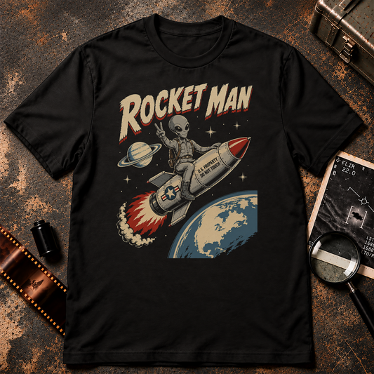 ROCKET MAN retro sci-fi design featuring a grey alien riding a U.S. government rocket into space while flashing a peace sign above Earth.