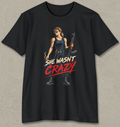 A black short-sleeve crewneck t-shirt with a graphic print of a woman holding an assault rifle, with the text 'SHE WASN'T CRAZY' in stylized red and white lettering.