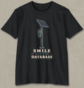A black short-sleeve crewneck t-shirt with a graphic of a solar-powered parking ticket reader and the text 'SMILE FOR THE DATABASE' printed on the front, displayed against a textured gray background.