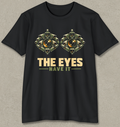 THE EYES HAVE IT shirt design featuring two giant eyes formed from clusters of olive surveillance cameras with glowing amber lenses on black.