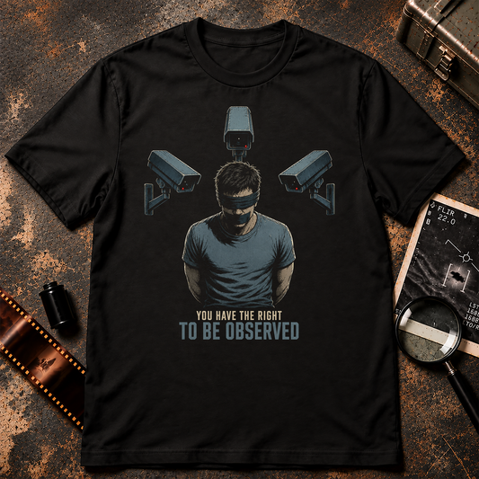 You Have the Right to Be Observed surveillance shirt design featuring a blindfolded man surrounded by three security cameras on a black background.