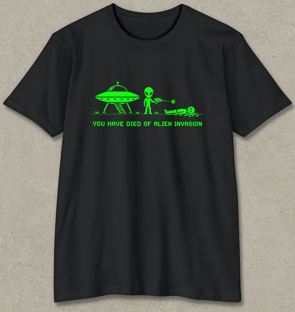 A black short-sleeve crewneck t-shirt with a bright green graphic of an alien, a UFO, and the text 'YOU HAVE DIED OF ALIEN INVASION' printed on the chest, displayed against a textured gray background.