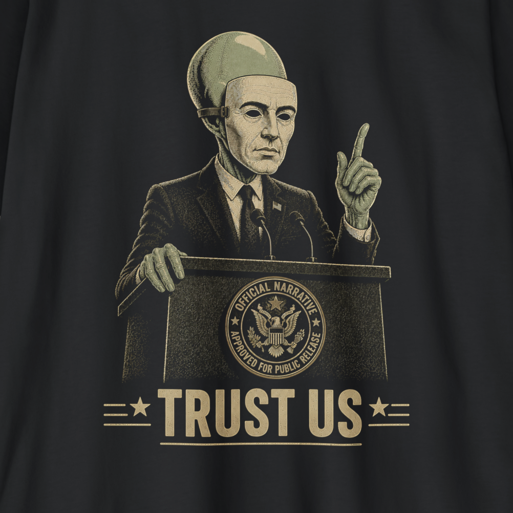 A close-up of a black t-shirt featuring a vintage-style graphic print of a man in a suit and a space helmet behind a podium with the text 'TRUST US' and a seal that reads 'OFFICIAL HATEORGANIZED POWERS FOR PUBLIC SAFETY'.