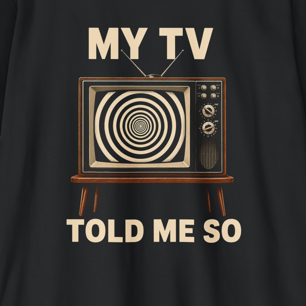 A close-up of a black garment featuring a retro graphic of a television with a hypnotic spiral screen and the text 'MY TV TOLD ME SO' in a light beige color.