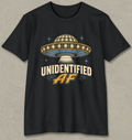 A black short-sleeve t-shirt with a retro-style graphic of a UFO and the text 'UNIDENTIFIED AF' in cream and gold, displayed against a textured gray background.