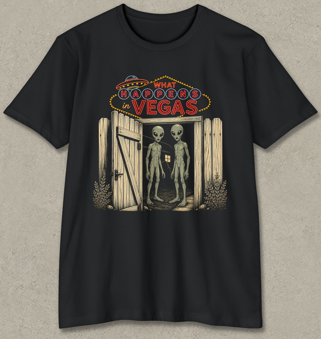 A black short-sleeve crewneck t-shirt with a graphic print on the front. The graphic features a neon sign reading 'WHAT BROOKERS IN VEGAS' above an open wooden door with two tall, thin gray aliens standing inside.