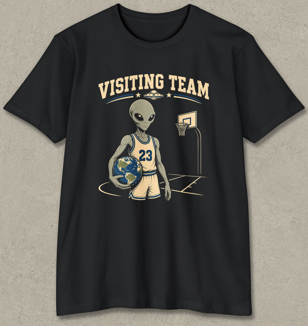 A black short-sleeve crewneck t-shirt featuring a graphic of a cartoon alien basketball player holding a globe, with the text 'VISITING TEAM' above him, displayed against a textured gray background.
