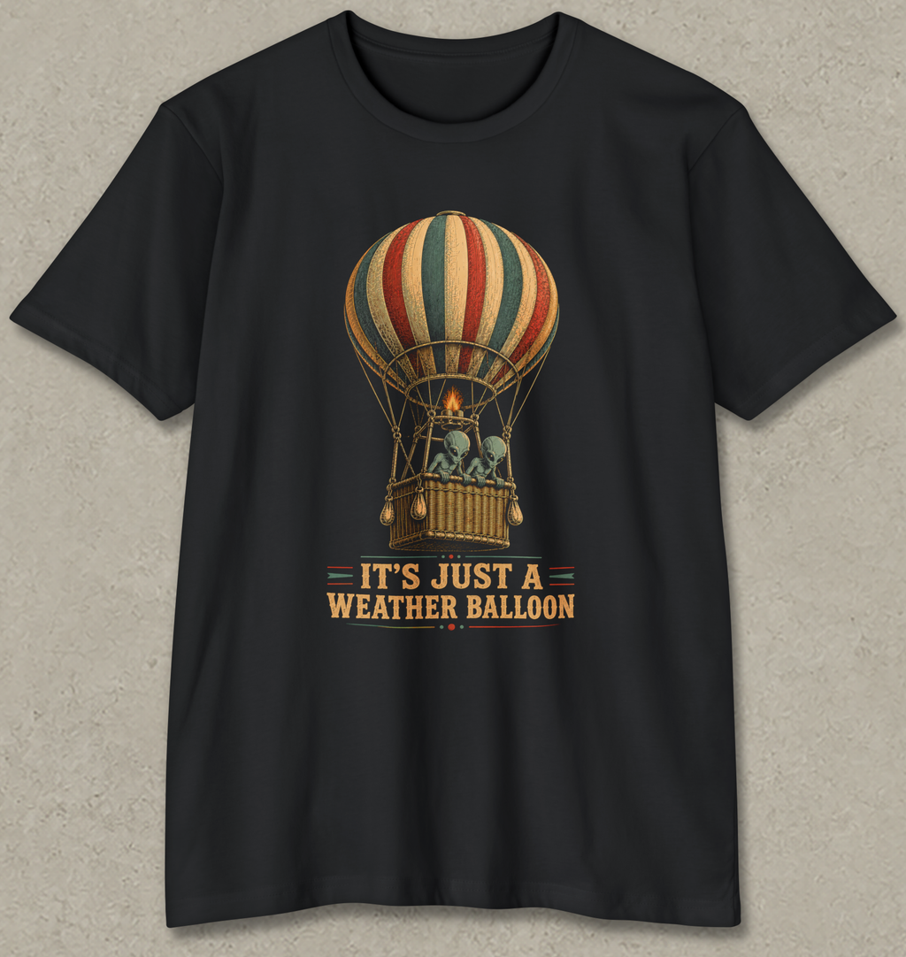 A black short-sleeve crewneck t-shirt featuring a vintage-style graphic of a striped hot air balloon with the text 'IT'S JUST A WEATHER BALLOON' printed below it, displayed flat against a textured gray background.