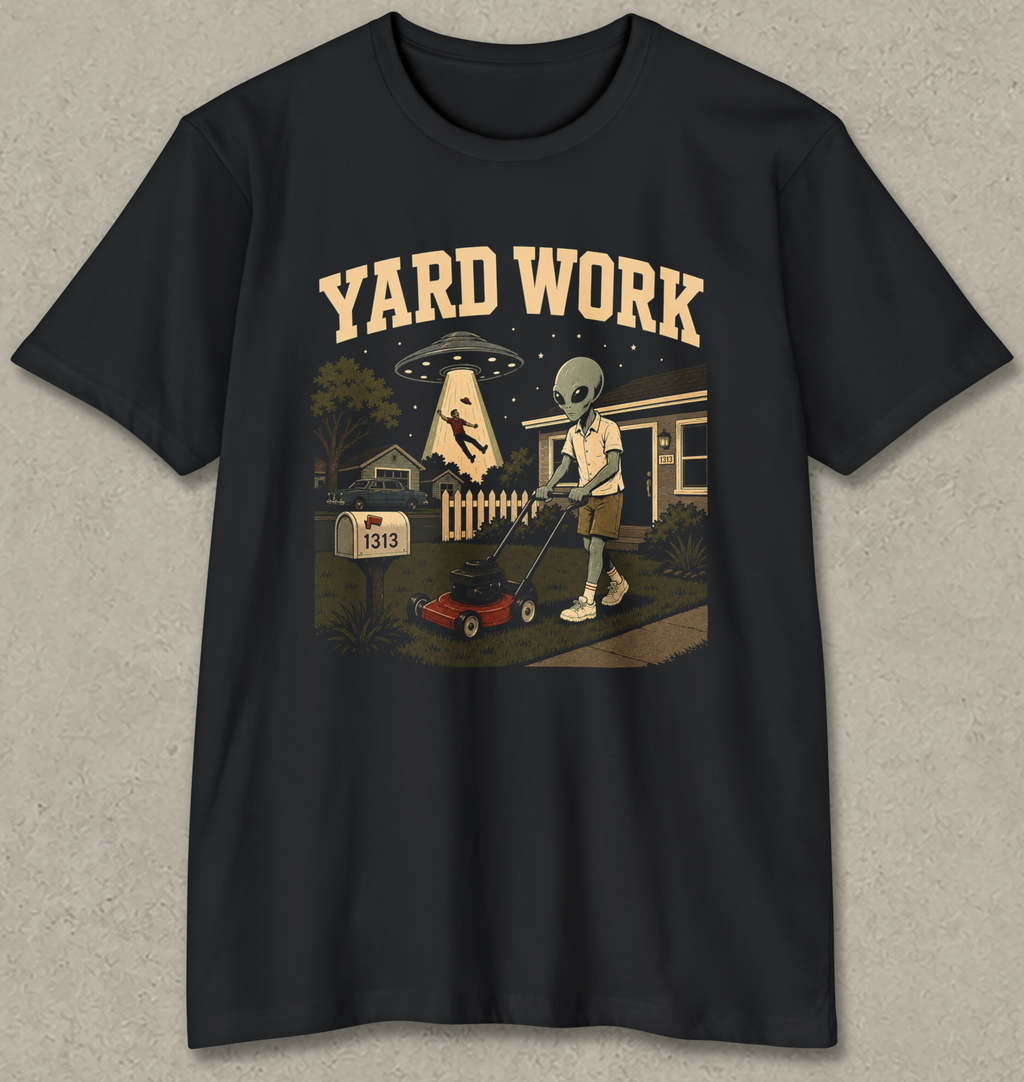 A black short-sleeve crewneck t-shirt with a vintage-style graphic on the front. The graphic features the text 'YARD WORK' in a retro cream font above an illustration of an alien mowing a lawn with a red lawnmower, with a UFO and house in the background.